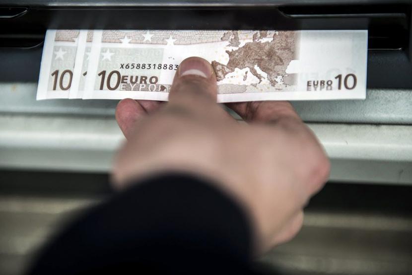 Klient wycofuje gotówkę z bankomatu. Fot. Bloomberg. Klient wycofuje gotówkę z bankomatu. Fot. Bloomberg.