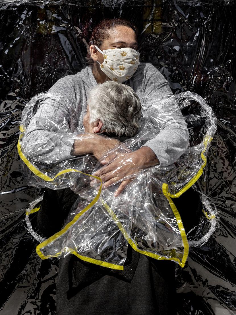 Mads Nissen, „Pierwszy uścisk”– zdjęcie roku 2021 i najlepsze zdjęcie w kategorii „News – zdjęcia pojedyncze”. Duński fotograf uwiecznił pielęgniarkę Adrianę Silva da Costa Souzai 85-letnią Rosę Luzia Lunardi, dla której to była pierwsza możliwość przytulenia się do człowieka od pięciu miesięcy. Domy opieki w Brazylii zostały zamknięte dla osób z zewnątrz ze względu na pandemię, a personel dostał polecenie ograniczenia kontaktu fizycznego z podopiecznymi. Foliowa „kurtyna do przytulania” umożliwiła przywrócenie tego kontaktu. Sao Paulo, 5 sierpnia 2020 r.