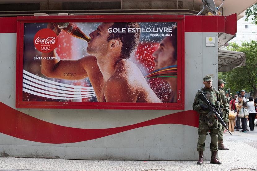 Brazylijski żołnierz stoi obok reklamy Coca-Coli umieszczonej niedaleko plaży Copacabana