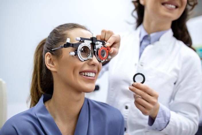 Ophthalmologist examining woman with optometrist trial frame. female patient to check vision in ophthalmological clinic