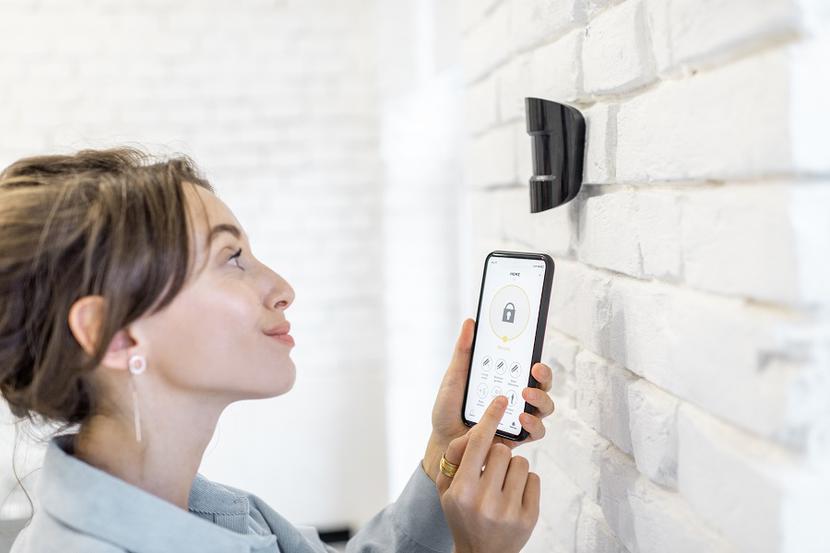 Kobieta steruje systemem alarmowym za pomocą smartfona Kobieta steruje systemem alarmowym za pomocą smartfona