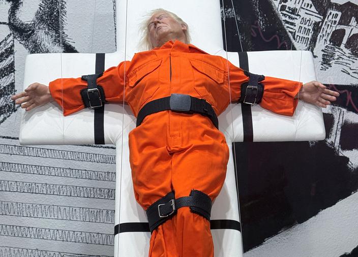 „Święty czy Grzesznik", rzeźba londyńskiego artysty Masona Storma przedstawiająca prezydenta USA Donalda Trumpa przywiązanego do krzyża jako więźnia skazanego na śmierć, jest eksponowana w galerii sztuki w Bazylei w Szwajcarii, 1 listopada 2025 r. Zdjęcie zrobione przez okno galerii.