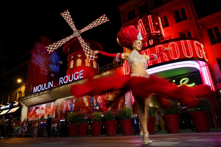 Tancerka kankana występuje przed kabaretem Moulin Rouge podczas uroczystości ponownego uruchomienia kultowego czerwonego wiatraka w Paryżu, Francja, 10 lipca 2025 r.