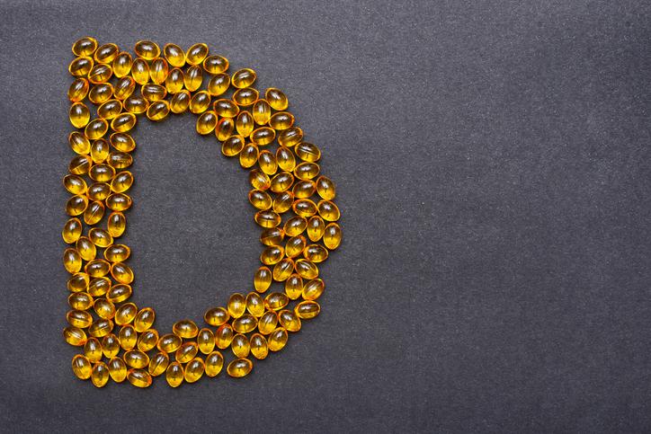 Vitamin D capsules laid out in the shape of the letter D on a black background. Health support and treatment. Biologically active additives. Vitamin D capsules laid out in the shape of the letter D on a black background. Health support and treatment. Biologically active additives.