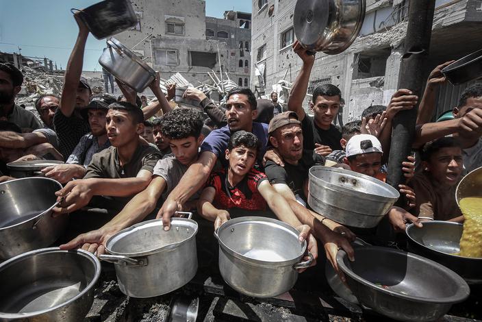 Wysiedleni Palestyńczycy odbierają ciepły posiłek z kuchni społecznej w Dżabaliji, w północnej Strefie Gazy, 19 maja 2025 r. Fot. Ahmad Salem/Bloomberg