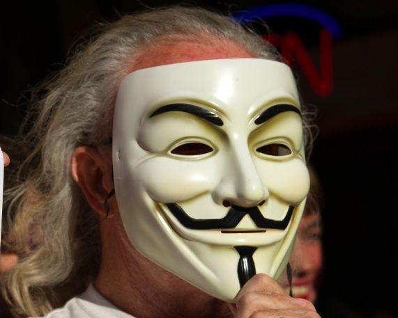 Mężczyzna w masce Guy'a Fawkesa, która jest symbolem grupy Anonymous (fot. Bloomberg)